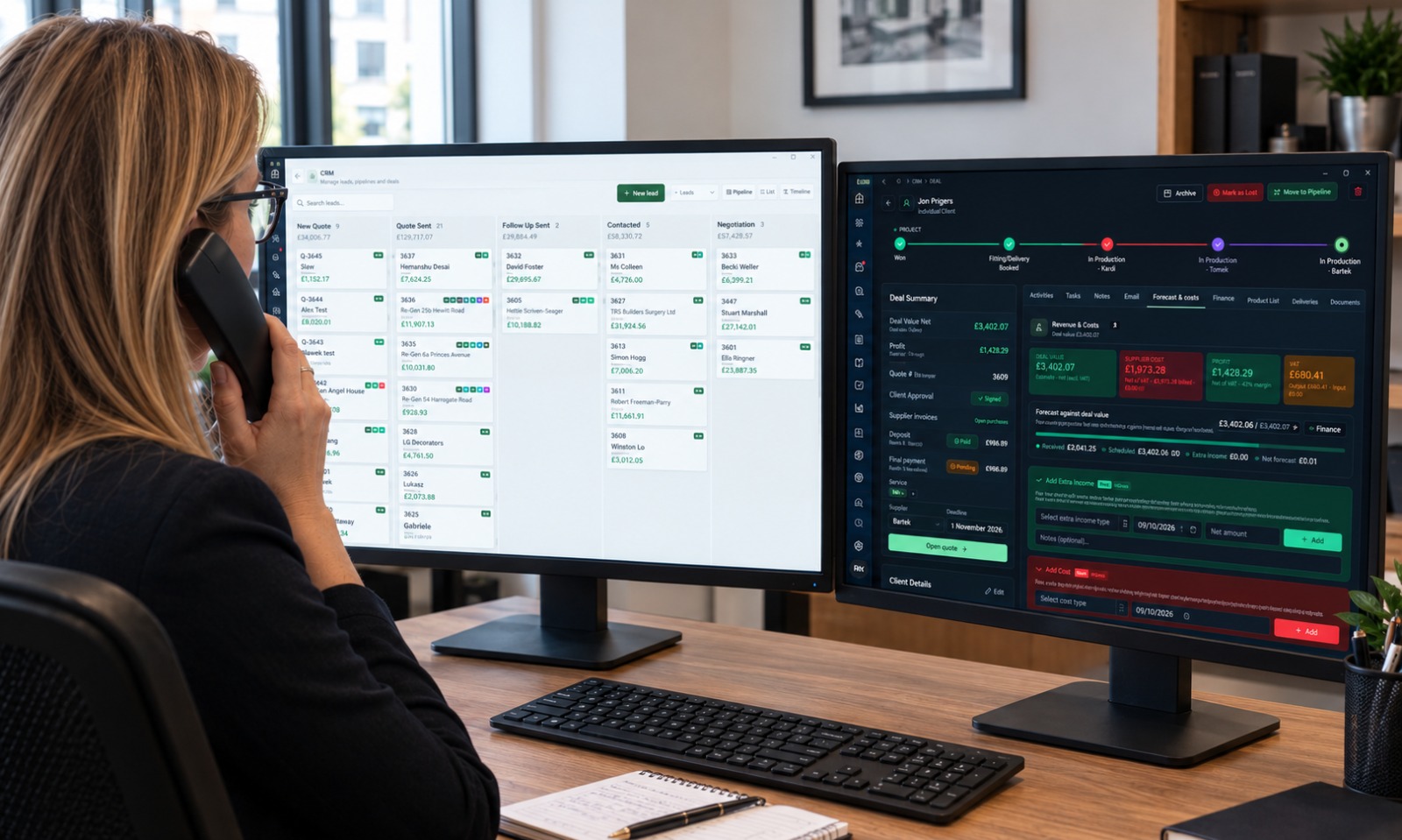 The Fenora workspace in use: two monitors on an office desk, one showing the CRM pipeline board, the other a live customer record, while the person at the desk speaks to the customer on the phone.